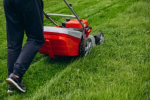 man cutting grass with lawn mover in the back yard